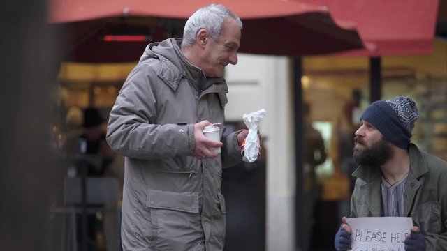 Hungry lonely  homeless receives breakfast from an old man