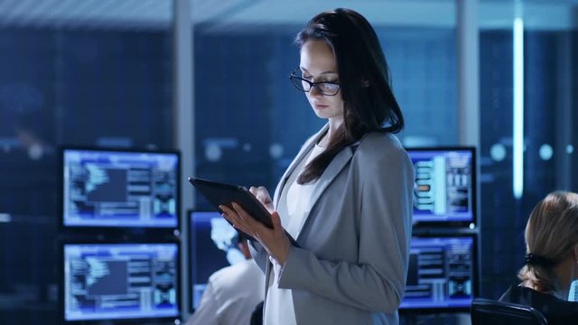 Young Female Government Employee Uses Tablet in System Control Center. Shot on RED EPIC-W 8K Helium Cinema Camera.