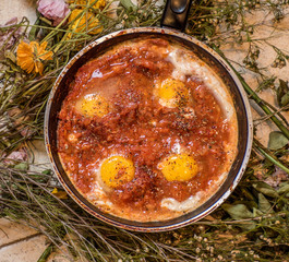 Shakshouka or shakshuka is a dish of eggs poached in a sauce of tomatoes, chili peppers, and...