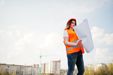 Engineer builder woman in uniform waistcoat and orange protective helmet hold business paper...