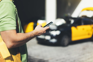 Man pointing finger on screen smartphone on background yellow taxi, tourist hipster using in hands...