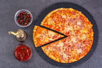 Pizza with ham and cheese on black stone