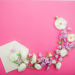 Floral pattern of white and pink flowers and paper envelope on pink background. Flat lay, top view. Flowers background.