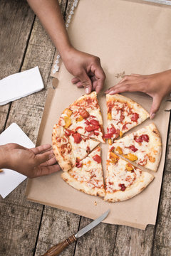 eating pizza together - hands and pizza on wooden background