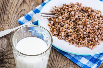 Glass with milk and boiled buckwheat porridge