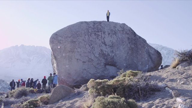 man stands on top of boulder after sending the climb
