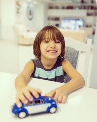 Happy kid at home with oldtimer car toy