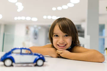 Happy kid at home with oldtimer car toy