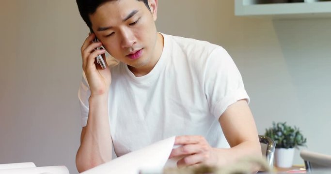Man looking at document while talking on mobile phone