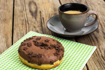 One donut in chocolate glaze on wooden background