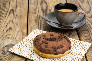One donut in chocolate glaze on wooden background