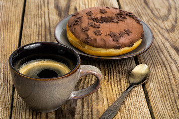 One donut in chocolate glaze on wooden background