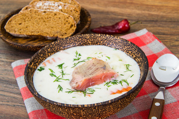 Fish cream soup with salmon in wooden bowl
