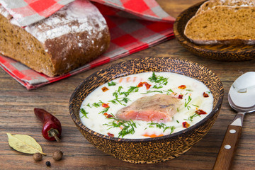 Fish cream soup with salmon in wooden bowl