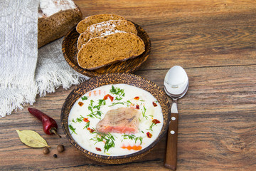 Fish cream soup with salmon in wooden bowl