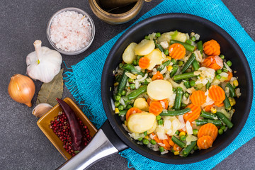 Frying pan with fried vegetables on blue napkin