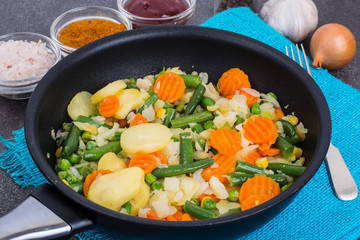 Frying pan with fried vegetables on blue napkin
