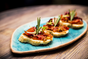 Bruschetta with tomato and vegetables decorated with rosemary On a blue plate