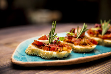 Bruschetta with tomato and vegetables decorated with rosemary On a blue plate