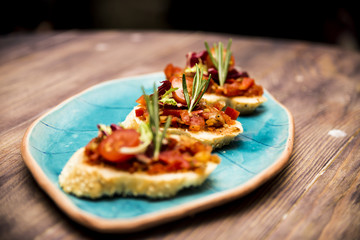Bruschetta with tomato and vegetables decorated with rosemary On a blue plate