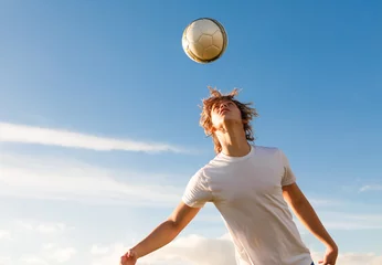 Gordijnen Male soccer / football player hitting the ball with his head.  © kieferpix