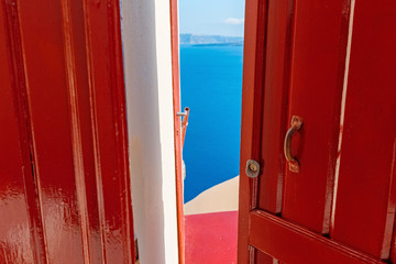 Colorful landscape with Wooden vinous doors and blue Aegean sea at background. Santorini island, Oia village famous summer resort with exquisite architecture , Greece, Europe.