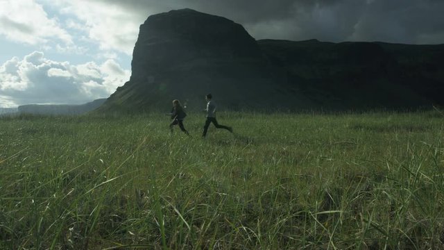 Man and woman playfully running through field
