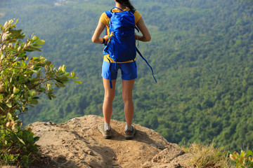 successful woman hiker enjoy the view on mountain peak cliff