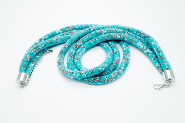on a white background lies a necklace on the neck with a blue gem