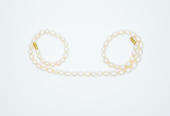 on a white background lies a pink pearl necklace on the neck