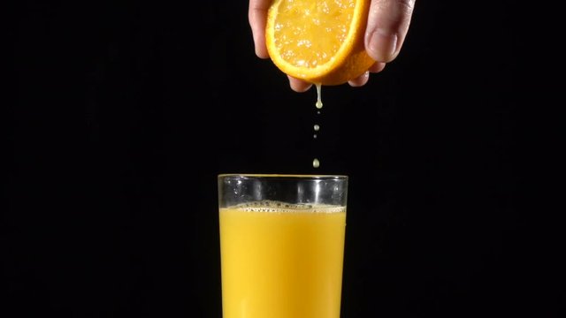 Hand squeeze the orange fresh juice in glass, slow motion