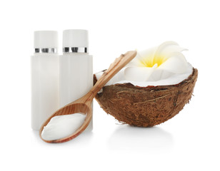 Fresh coconut, bottles with cream and wooden spoon on white background
