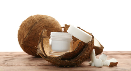 Jar with cream in coconut rind on wooden table