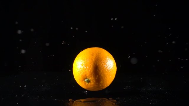 falling orange fruit on black background, slow motion