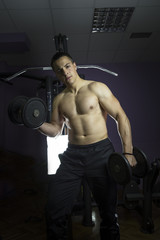 Fototapeta na wymiar Sports bodybuilder young man hard training muscles workout in gym