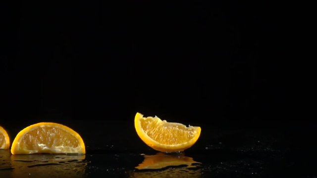 falling orange slices on black background, slow motion