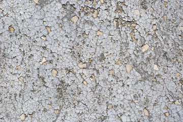 peeling off the gray surface of a cement wall