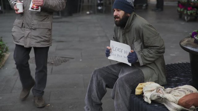 Portrait of homeless sit on the street ,man helping him with food and coffee