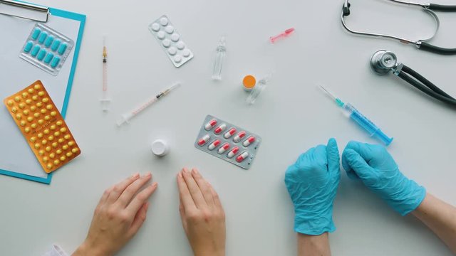 Doctor show some pillo to his assistant and he choose wright tablet . Top view.