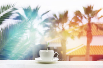 cup of tea on the summer porch on a background of palm trees Sun Through Palm leafs .good morning concept. Colored sunset and light.relax and detox tea.happy Toned Design View