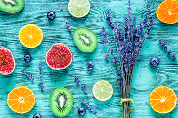 Pattern cut citrus, lavender bouquet, blueberry on blue desk background top view