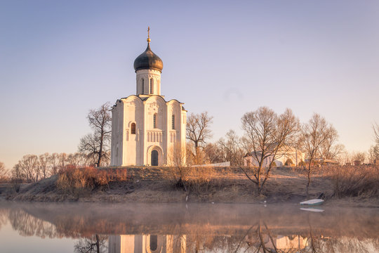 The mist-shrouded lake in front of the ancient church, a frosty morning
