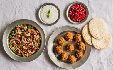 Crispy falafel, Arab pita bread with pomegranate seeds and white sour cream sauce against white background. Selective focus.