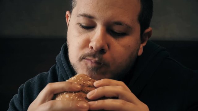 Close up on a hungry man who grabs a burger voracious
