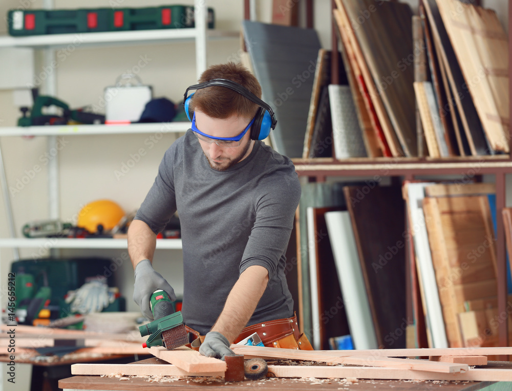 Wall mural Handsome young carpenter in workshop