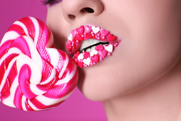 Beautiful young woman with creative makeup and lollipop on color background, closeup