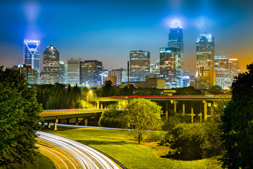 Traffic light trails in Charlotte, North Carolina. The city skyline glows on a foggy night.