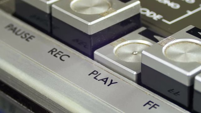 Pushing Play Button on a Vintage Tape Recorder. Close-up. Pushing a Finger Button Play. Man finger presses playback control buttons on audio cassette player.