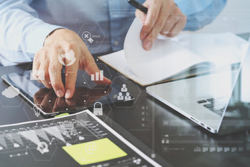 close up of businessman working with smart phone and digital tablet and laptop computer  on wooden desk in modern office with virtual icon diagram