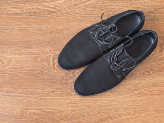Black mens shoes on a wooden floor.